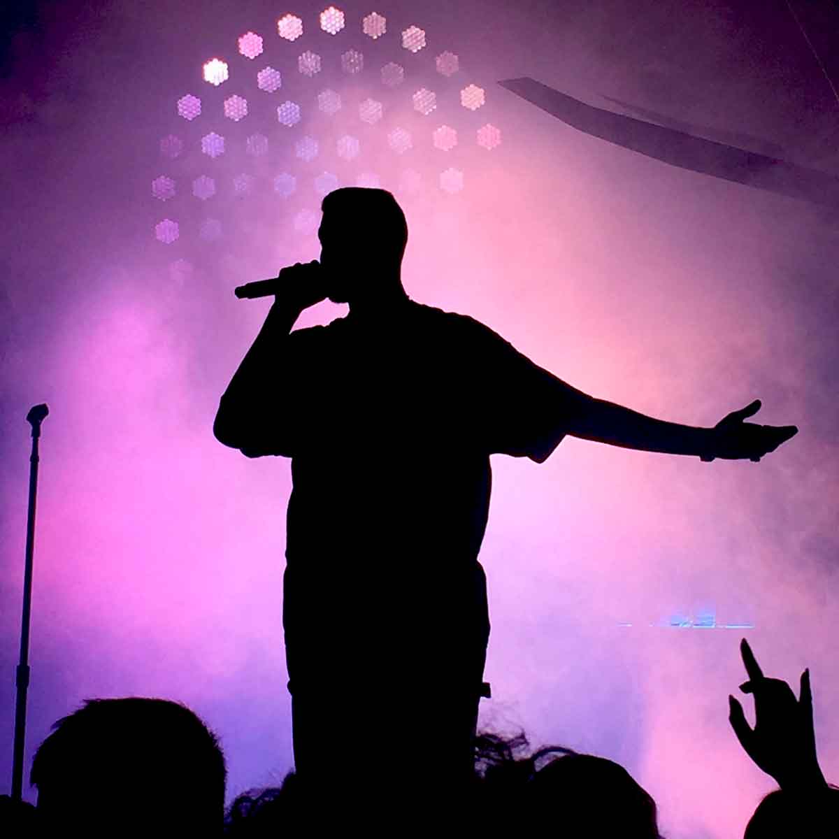 Silhouetted singer on stage with a purple background behind them