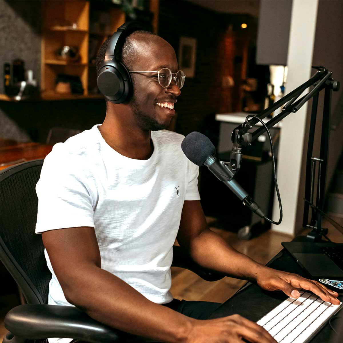 African American male sitting at desk doing a podcast.